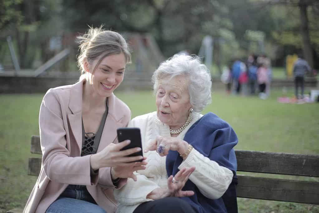 Cheerful senior mother and adult daughter using smartphone together