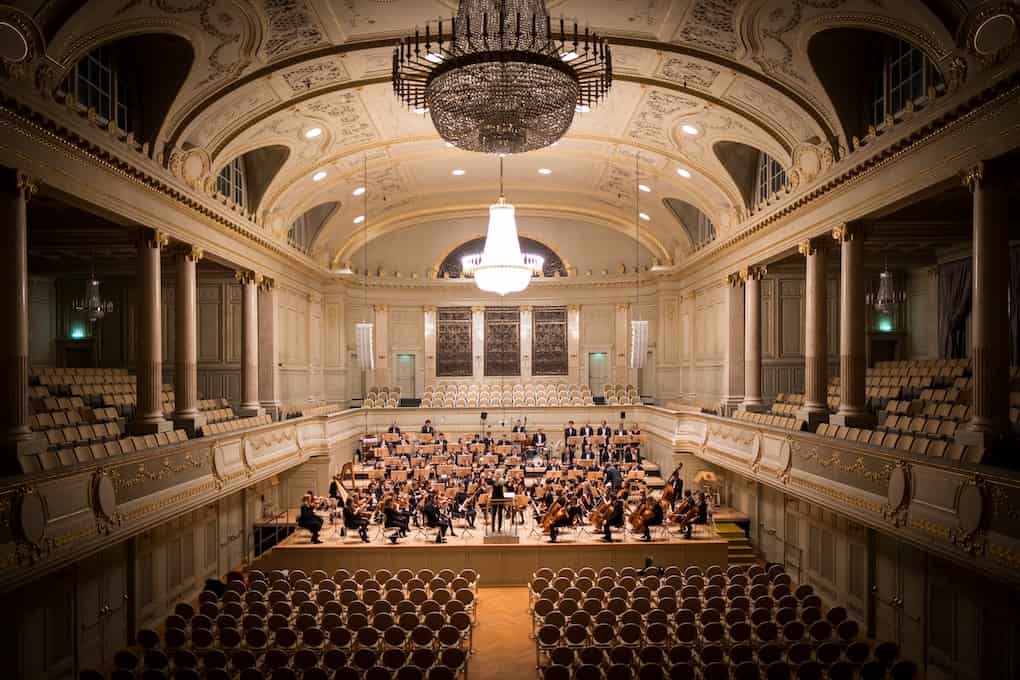 music group performing on stage with empty audience seats