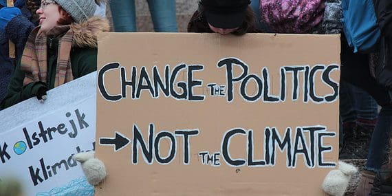person holding change the politics not the climate printed board