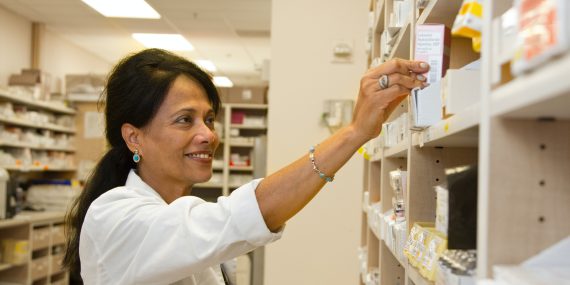 A female pharmacist is selecting a drug from the pharmacy inventory.