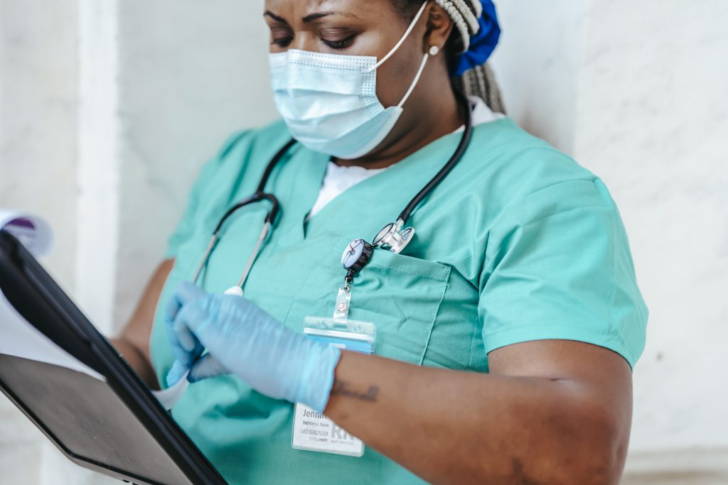 Crop nurse in mask and gloves with papers
