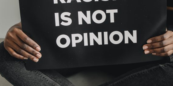 Woman in black tank top holding a poster on racism