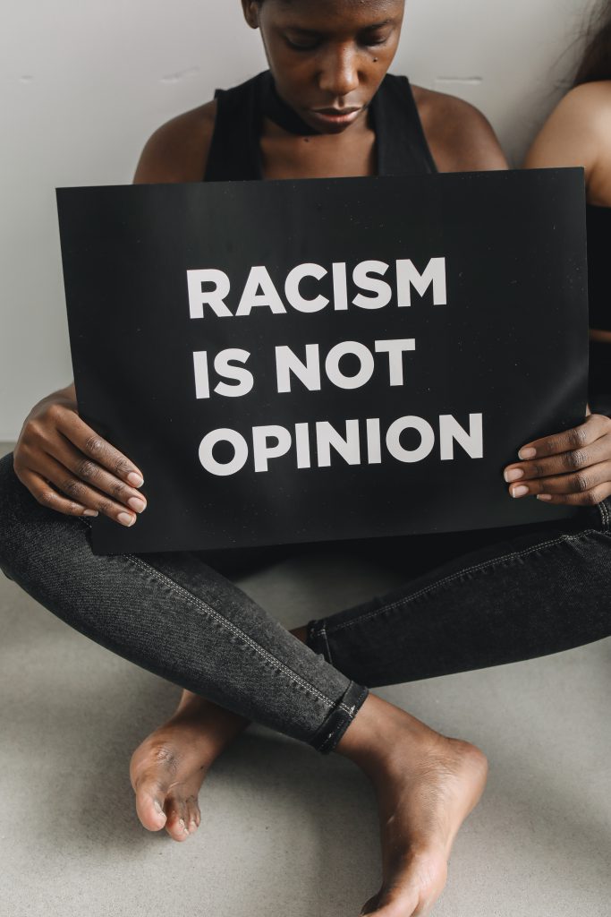 Woman in black tank top holding a poster on racism