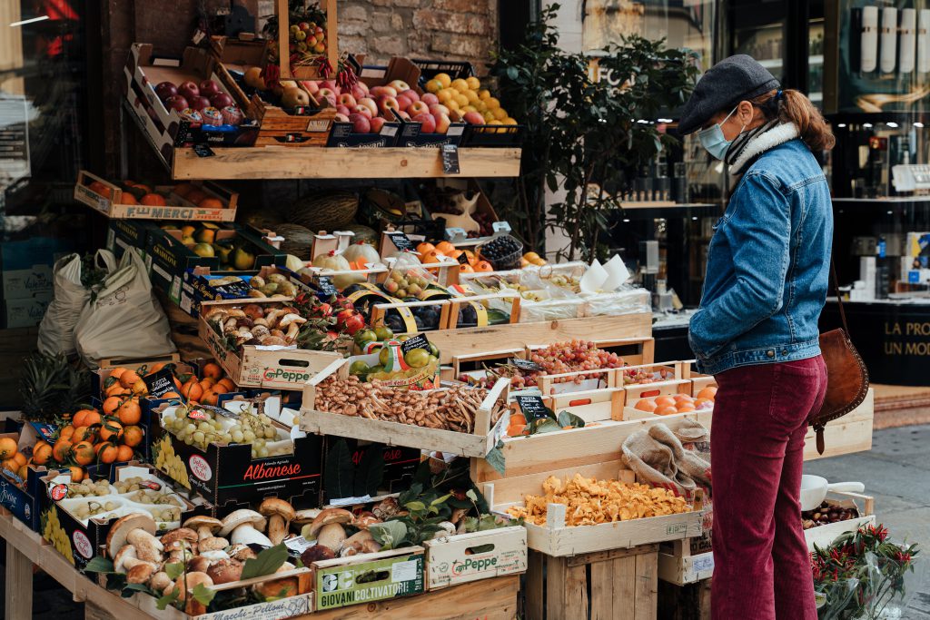 A trendy woman wearing a face mask shops at a market stall in Parma, Italy