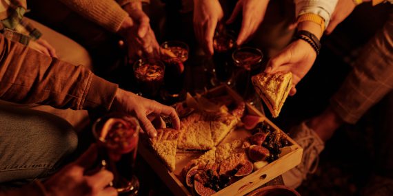 Crop friends sharing pie with mulled wine on party
