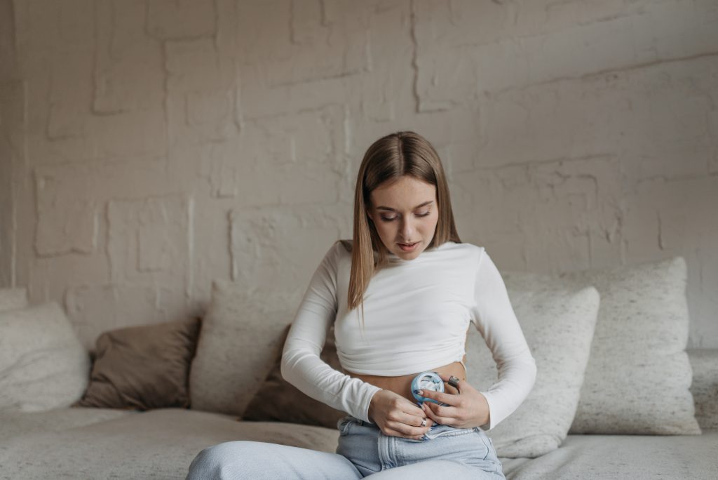 A woman wearing crop top while busy installing insulin pump on her abdomen