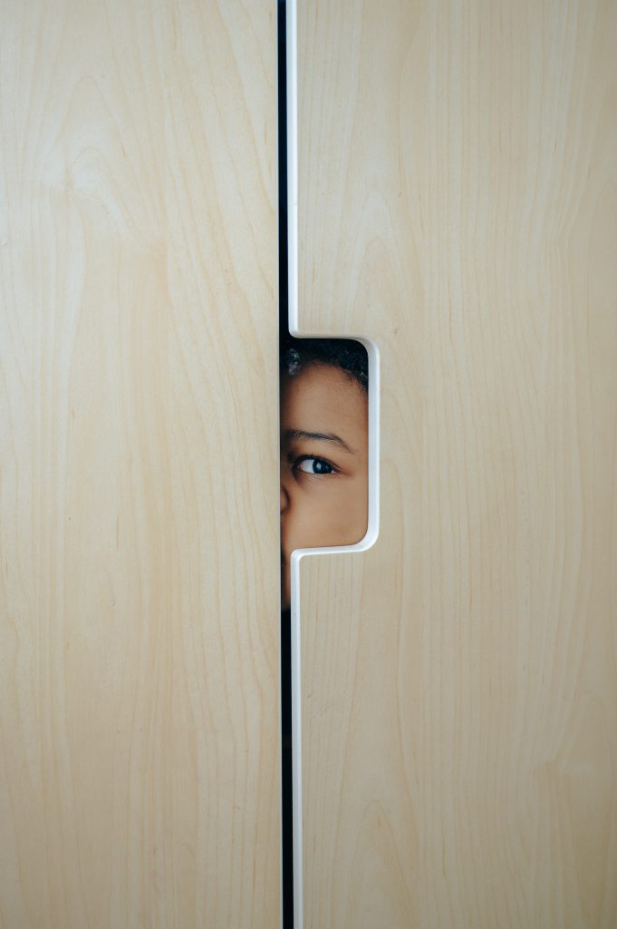 Anonymous black little kid hiding in wardrobe