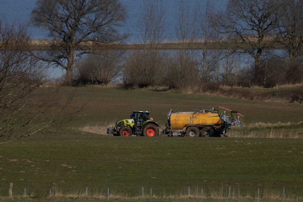 Claas tractor on meadow delivering manure and got stuck