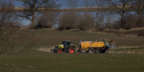 Claas tractor on meadow delivering manure and got stuck