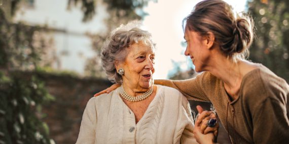 Joyful adult daughter greeting happy surprised senior mother in garden