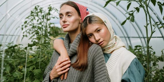 Young Women Standing in a Greenhouse with Growing Tomatoes