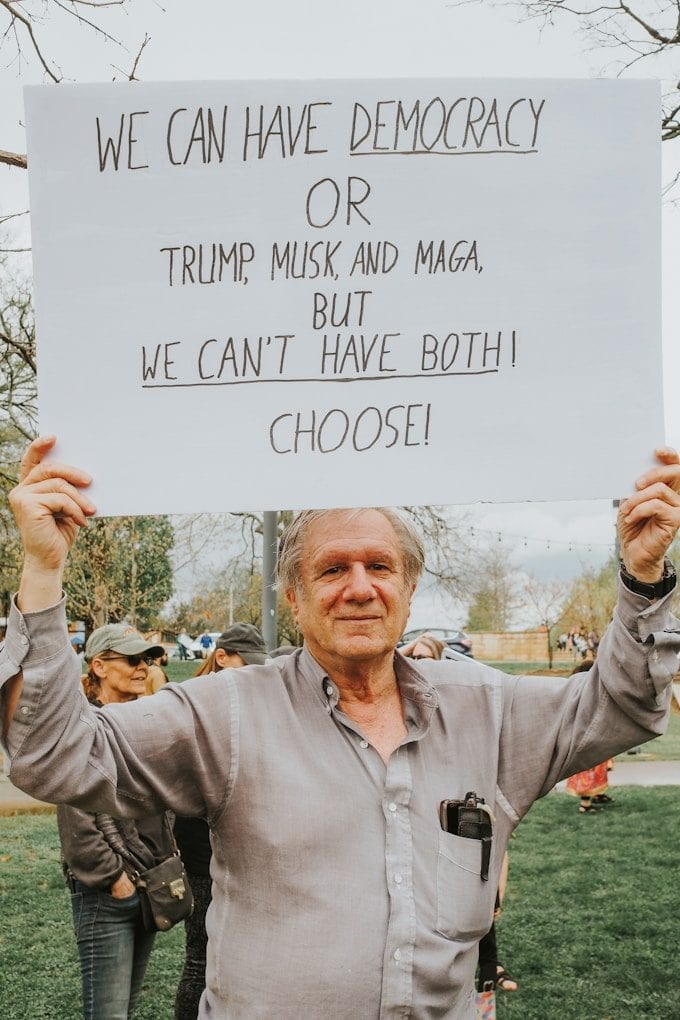 Protester holds sign condemning trump, musk, and maga.