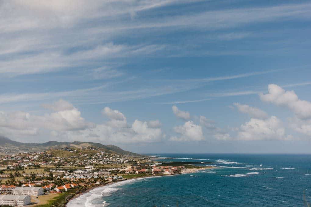 A picturesque aerial view of a coastal town with ocean waves and blue sky in the background.