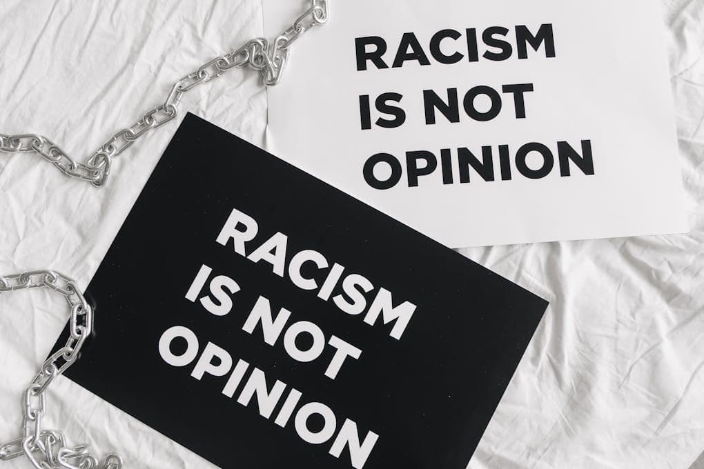 Black and white protest signs reading 'Racism is Not Opinion' on white fabric.