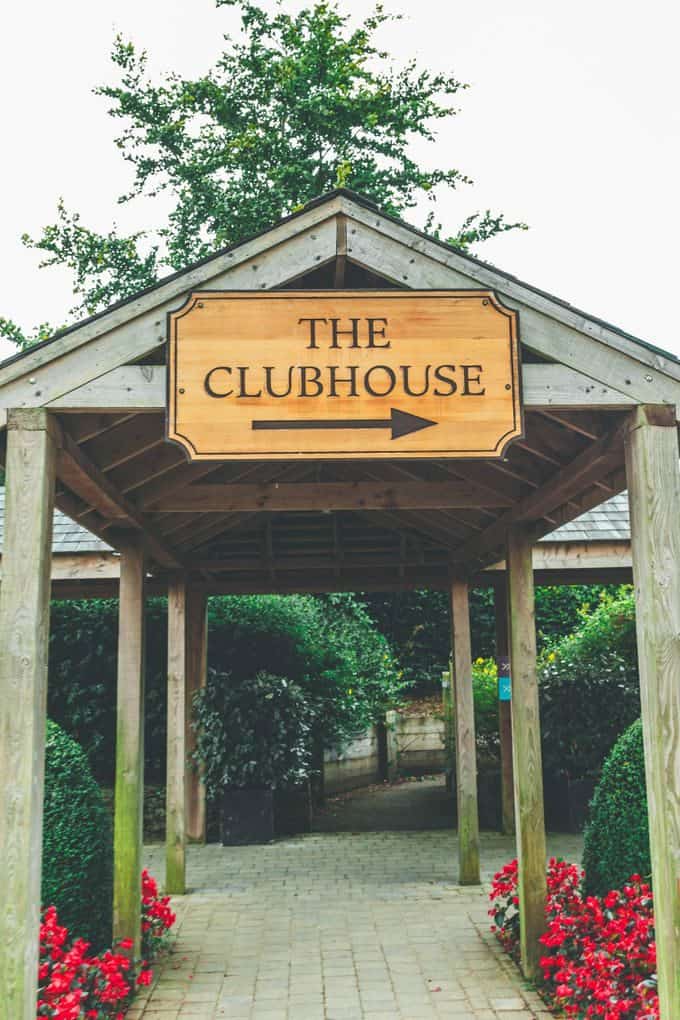 Inviting wooden sign leading to a clubhouse entrance surrounded by greenery at Fota Island Resort, Ireland.