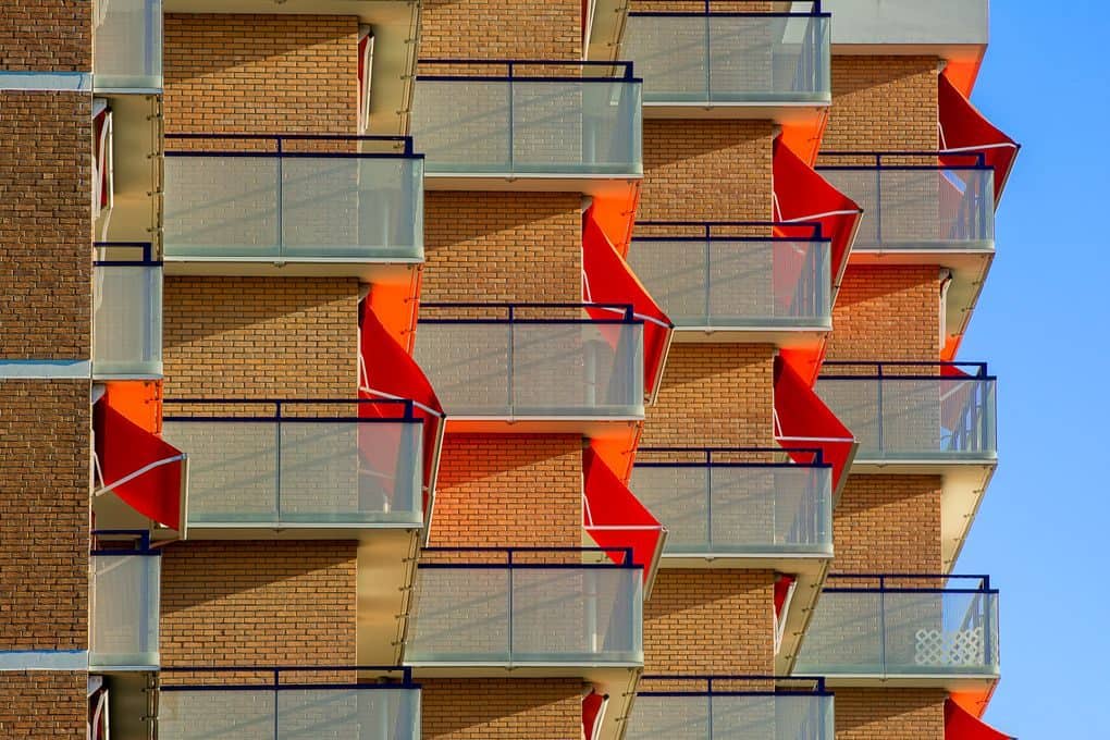 Close-up of a modern building's striking geometric balconies against a clear blue sky.