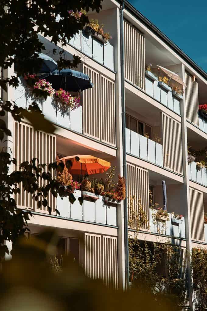 A picturesque view of modern Berlin balconies adorned with vibrant flowers and umbrellas.