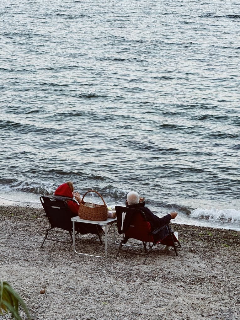 Elderly couple enjoying a peaceful picnic by the lake, capturing love in nature.