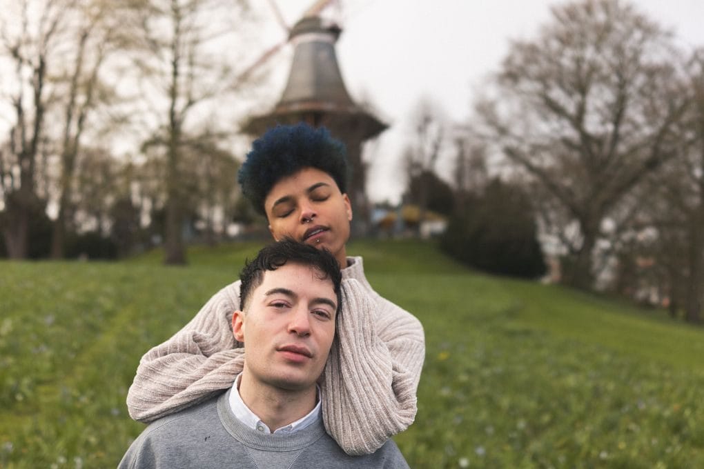 A couple embraces in front of a windmill in Bremen, Germany, showcasing love and serenity.