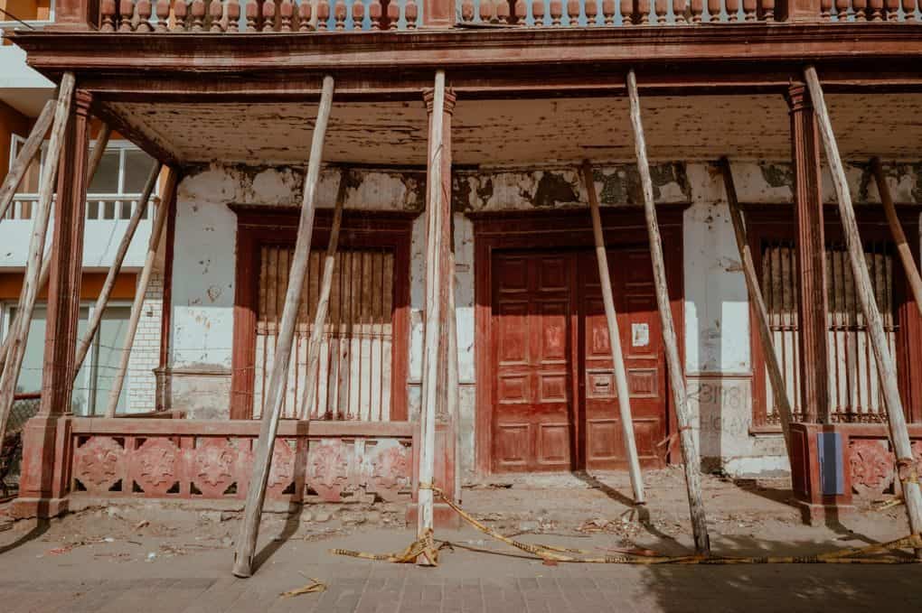 Detailed view of a historic building in Pacasmayo, Peru, showing restoration efforts with wooden supports.